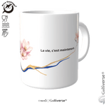 Weißer Keramikbecher mit dem Spruch „La vie, c’est maintenant“, Magnolienblüten und blau-goldenen Linien im Kintsugi-Look.